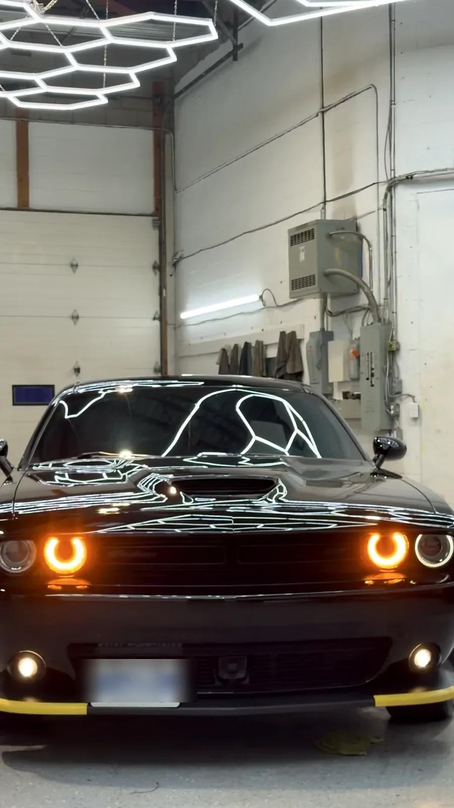 Black Dodge Challenger with amber halo headlights in the Cosmo Car Customs studio
