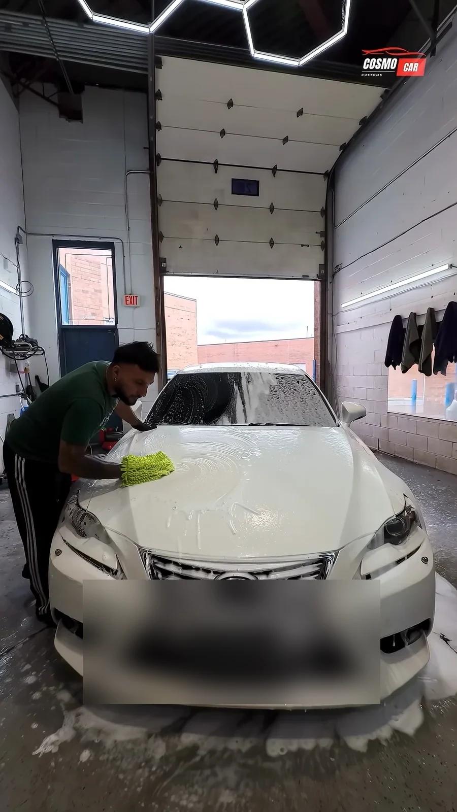 Cosmo Car Customs technician hand-washing a white Lexus with snow foam