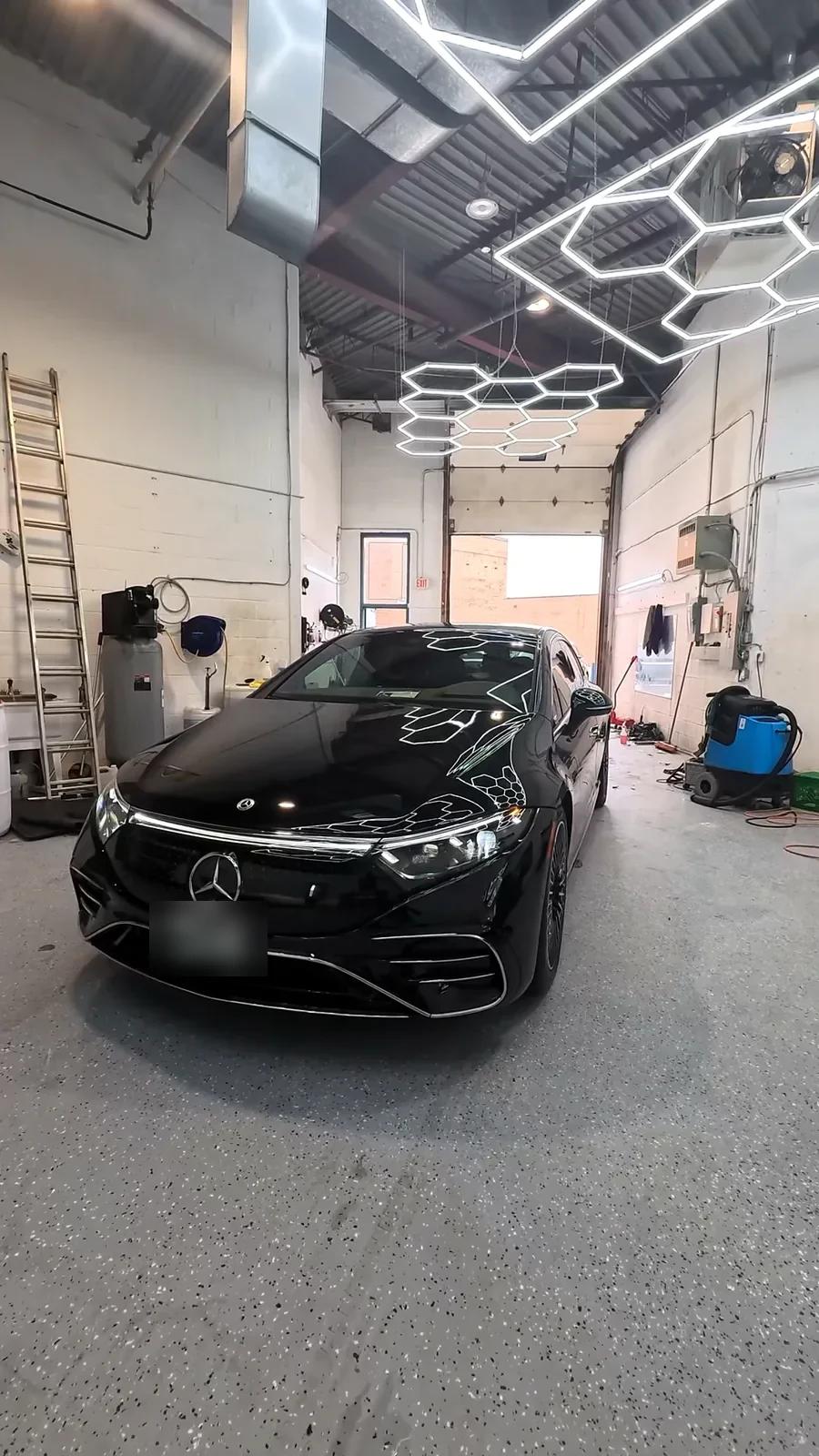 Black Mercedes-Benz EQS with a mirror gloss finish under the studio hex lights
