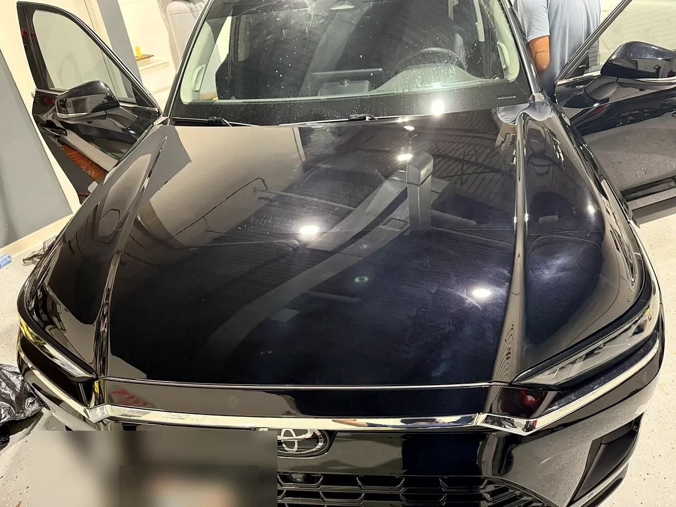 Close-up of a glossy black hood after paint correction and ceramic coating