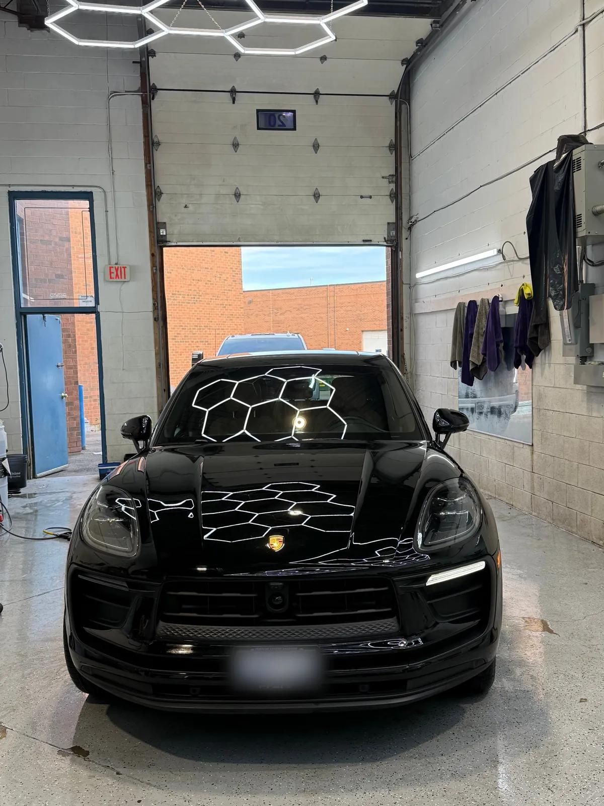 Black Porsche Macan reflecting the studio hex lights after a detail and wax at Cosmo Car Customs