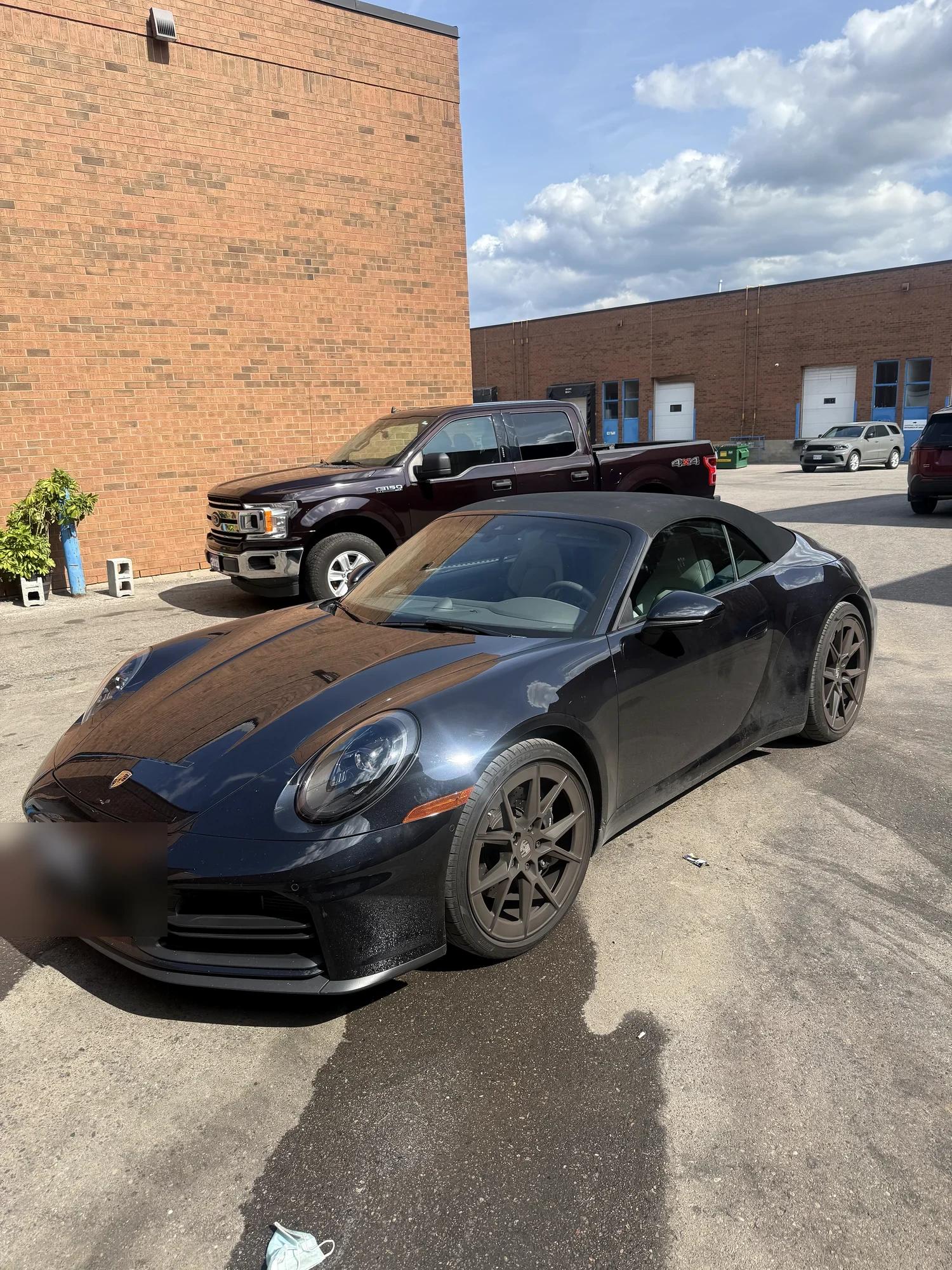 Black Porsche 911 Cabriolet arriving at the studio, dusty from the road