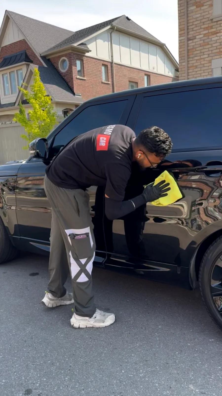 Technician polishing the rear quarter of a black car