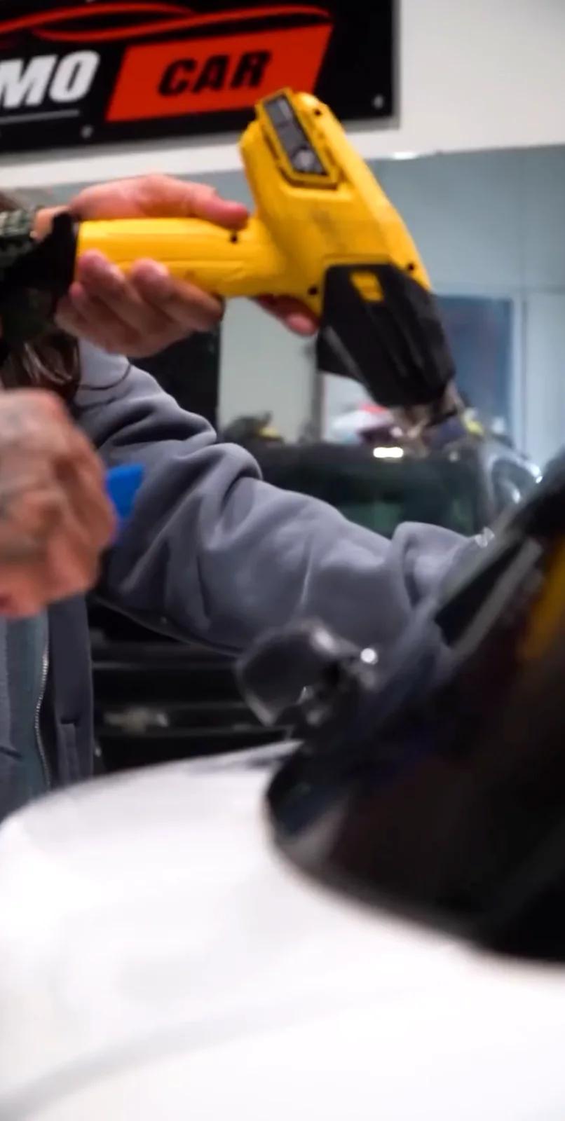 Heat gun shaping window film against the glass during installation
