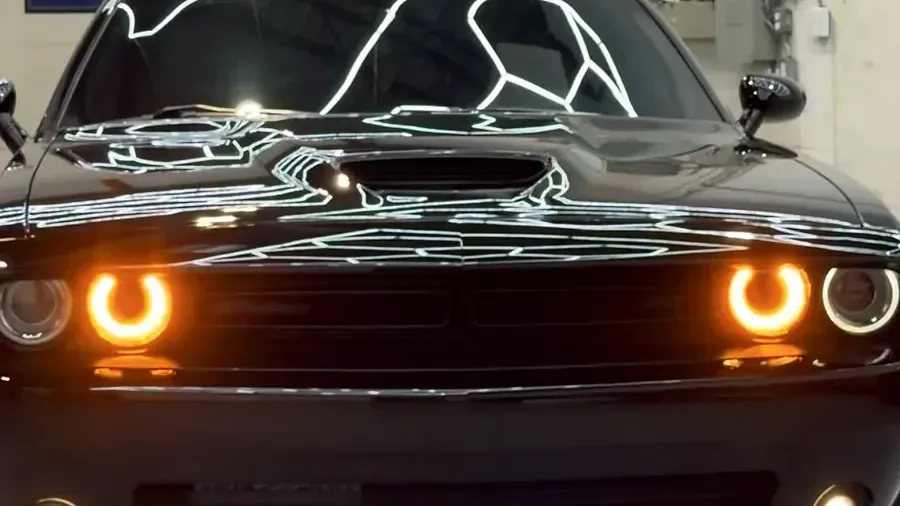 Black Dodge Challenger with its headlights on in the Cosmo Car Customs studio