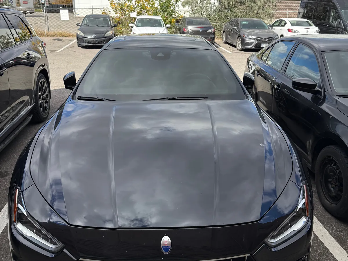 Black Maserati Ghibli outside the Mississauga studio with clouds reflecting in the freshly detailed hood