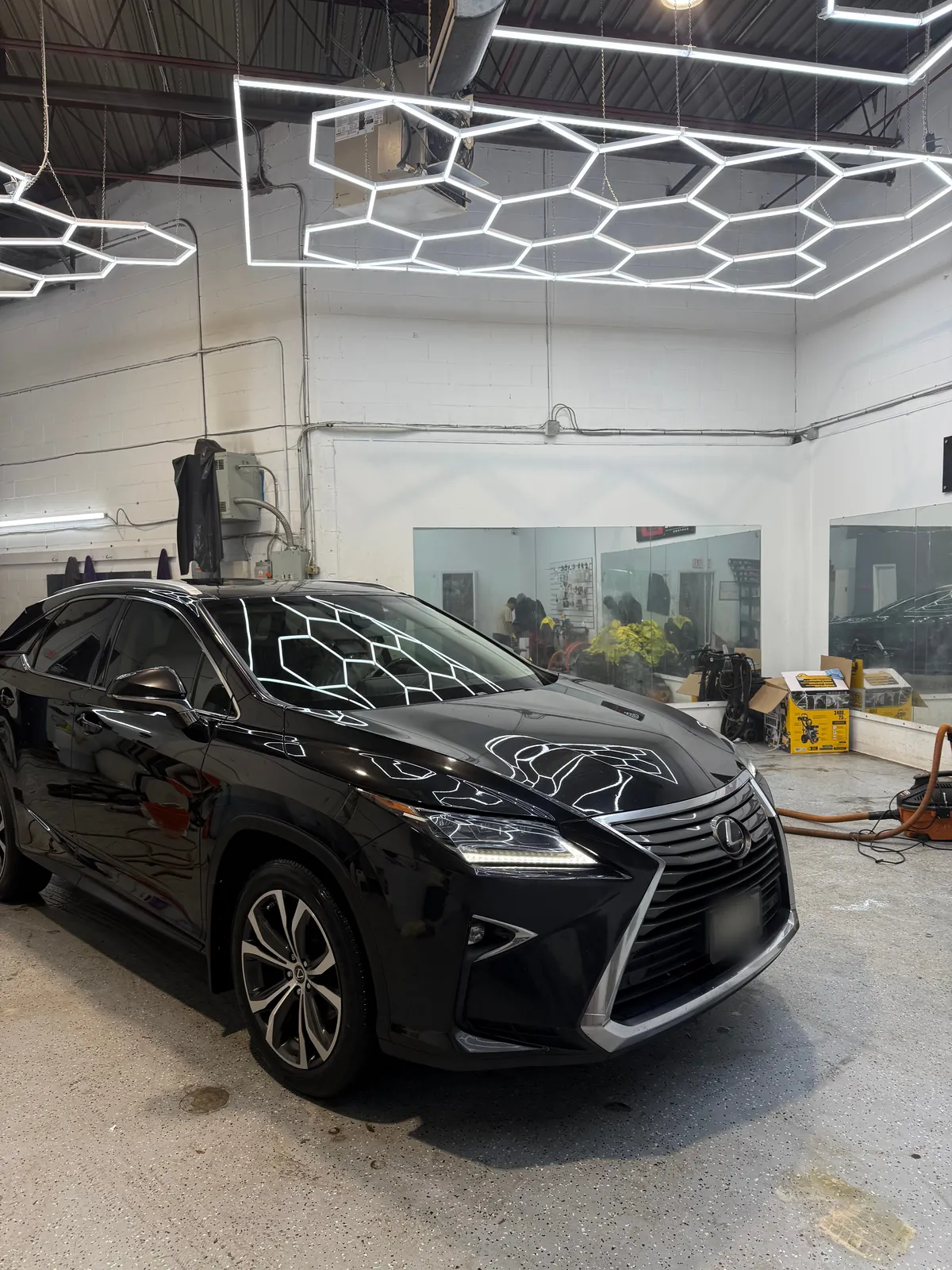 Black Lexus RX with a deep gloss finish under the studio hex lights after a detail